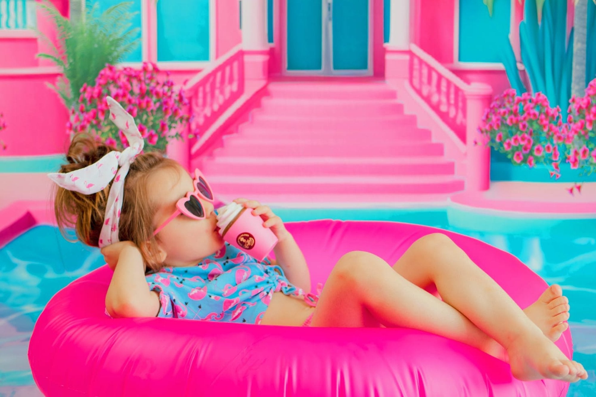 Une petite fille assise sur une bouée rose avec de la glace dans les mains