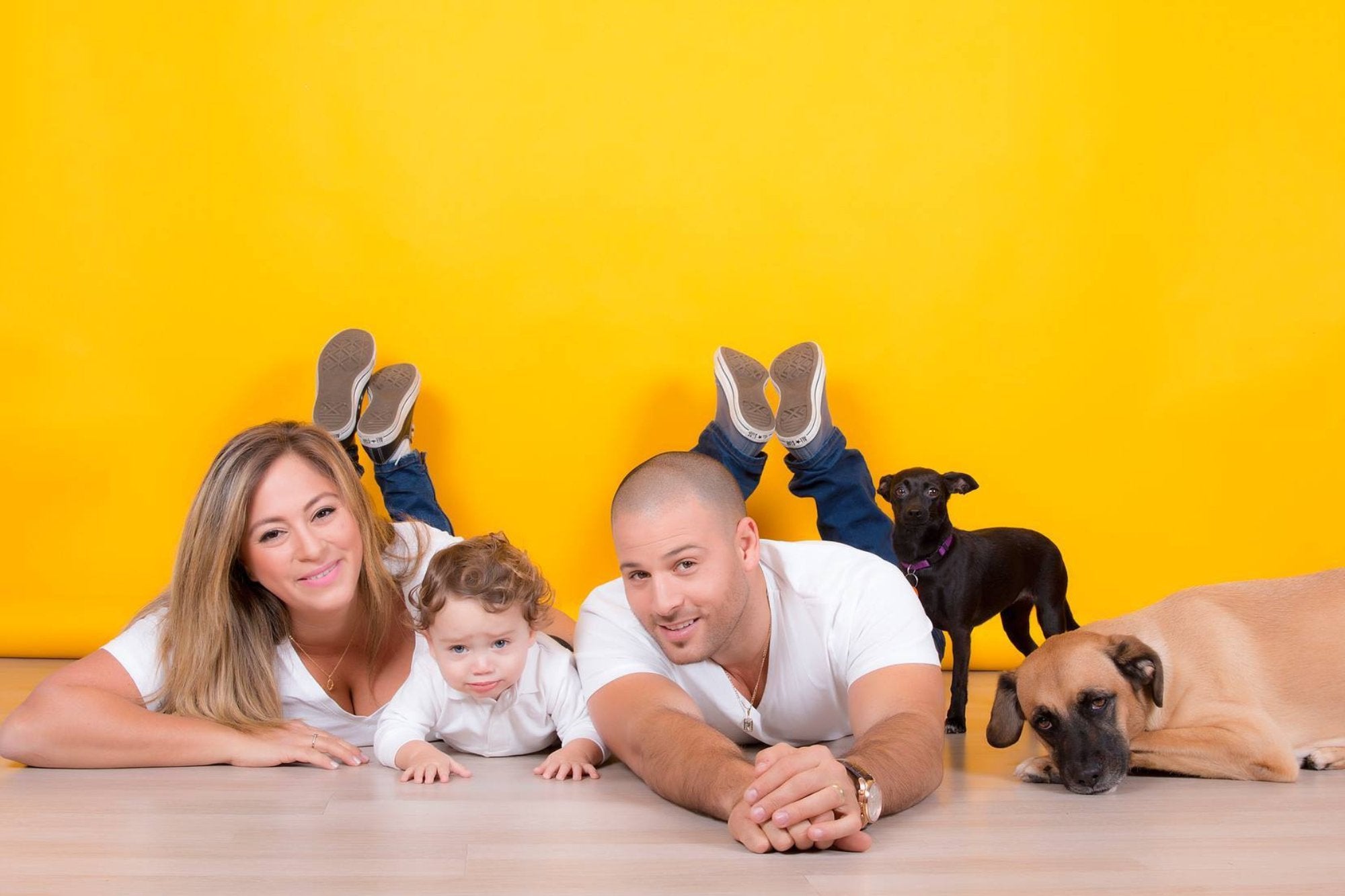 Maman et papa avec un enfant et un chien devant un fond de papier jaune