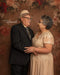 Grand-père et grand-mère se regardent affectueusement, debout devant un fond floral abstrait vintage